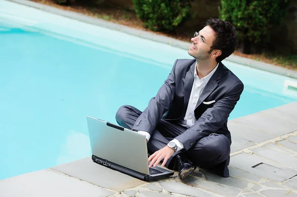 Jungunternehmer mit Computer neben Schwimmbad — Stockfoto