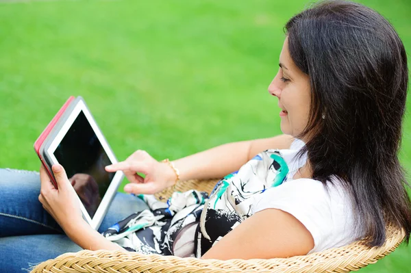 Mujer joven usando tableta al aire libre puesta en la hierba —  Fotos de Stock