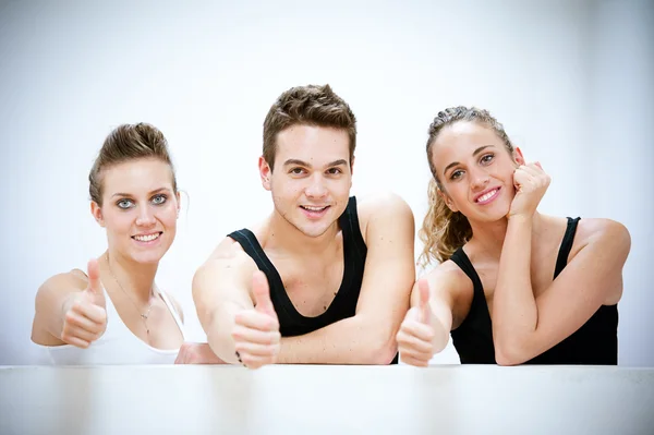 Drie lachende personen na fitness oefeningen met Duimschroef opwaarts Stockfoto