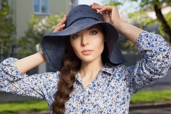 Scared girl keeping her hat with hands — Stock Photo, Image