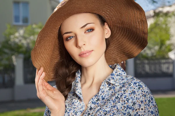 Chica con trenza manteniendo sombrero con la mano — Foto de Stock