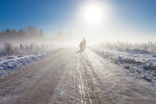 Mother and child on foggy snow farm road — Stockfoto