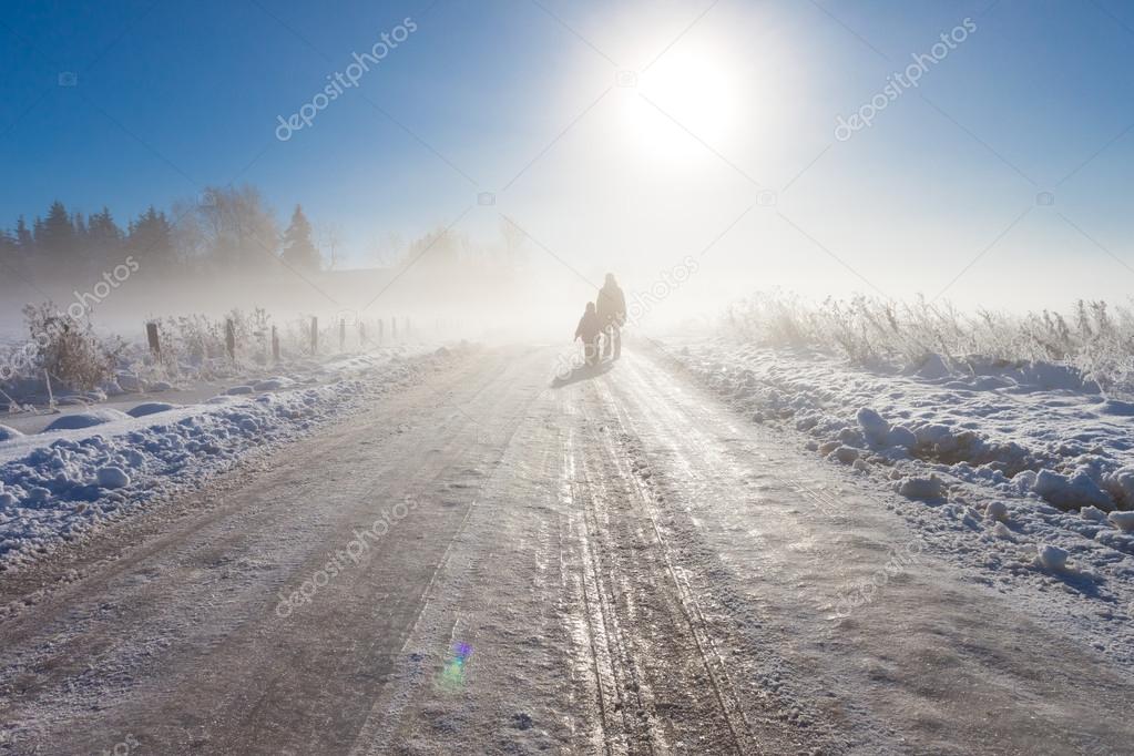 Mother and child on foggy snow farm road