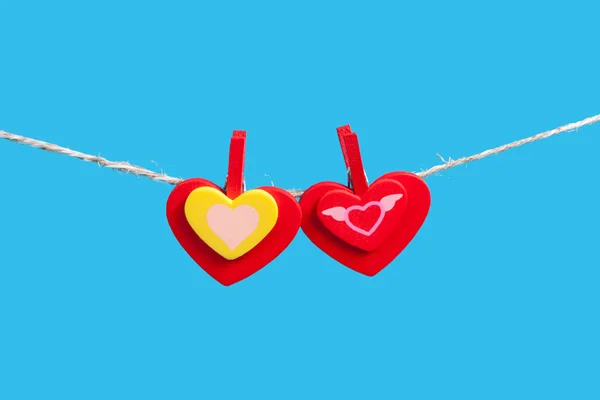 Hearts on clothesline with clothespins, blue background — Stock Photo, Image