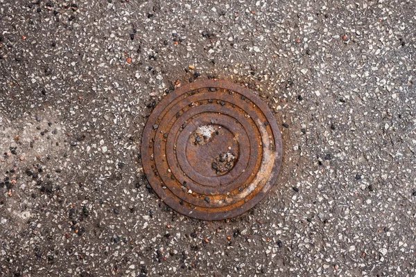 Rusty hatch cover on asphalt road Stock Photo