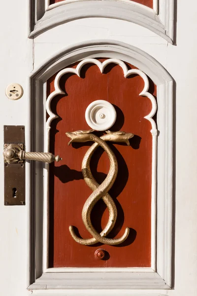 Door decorated with crossed golden serpents and intricate brass — Stock Photo, Image