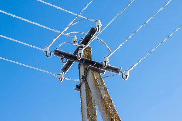 Stromleitungen tropfen mit Eiszapfen gegen blauen Himmel — Stockfoto