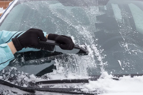 Vrouw schoonmaken sneeuw van de auto — Stockfoto