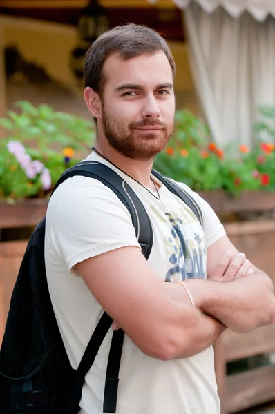 Porträt eines jungen Mannes mit Rucksack. Arme verschränkt anschauen — Stockfoto