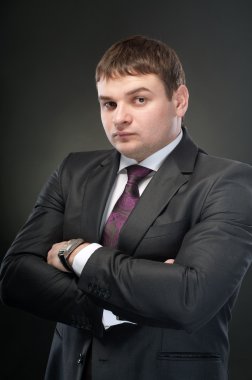 Kollarını göğsünde arasında katlanmış ile genç bir adam duruyor. karanlık bir arka plan üzerinde.