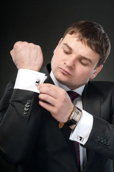 Молодой человек застегивает запонки и часы в рамке . — стоковое фото