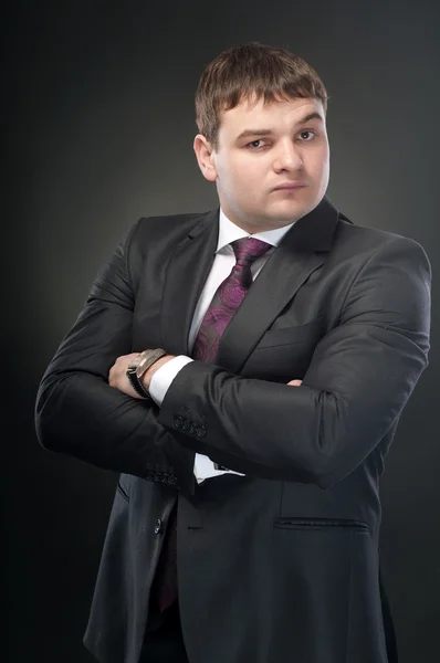 A young man stands with his arms folded across his chest. On a d — Stock Photo, Image