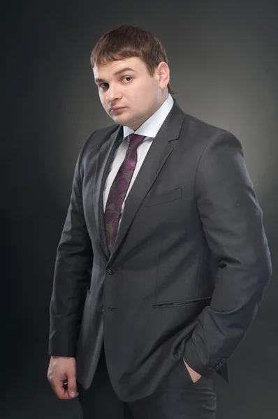 A businessman in a suit standing with his hand in his pocket and — Stock Photo, Image