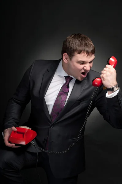 Man shouting into a red telephone. — Stock Photo, Image