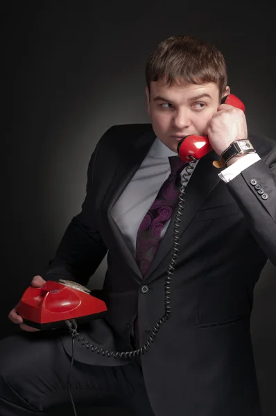 A man talking on a red phone. — Stock Photo, Image