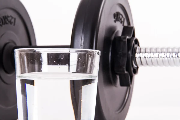 Glas water en zwarte barbell — Stockfoto