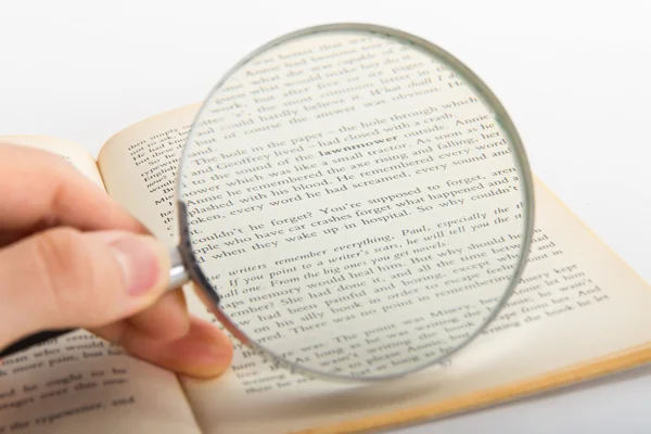 Hand Holding Magnifying Glass on Novel — Stock Photo, Image