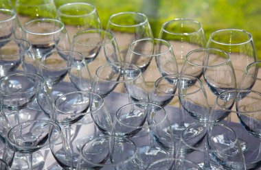 İnce saplı bir tepside duran çok sayıda parlak cam bardak.