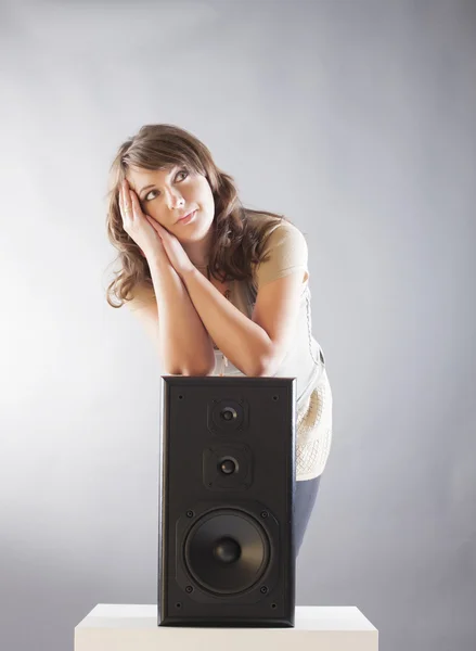Beautiful woman with hands on big wooden speaker — Stock Photo, Image