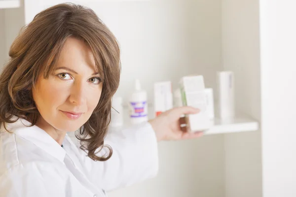 Mulher jovem farmacêutica com uma garrafa de medicamentos — Fotografia de Stock