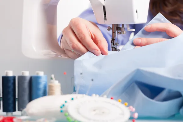 Manos en la máquina de coser con carretes de hilos de color y costura —  Fotos de Stock