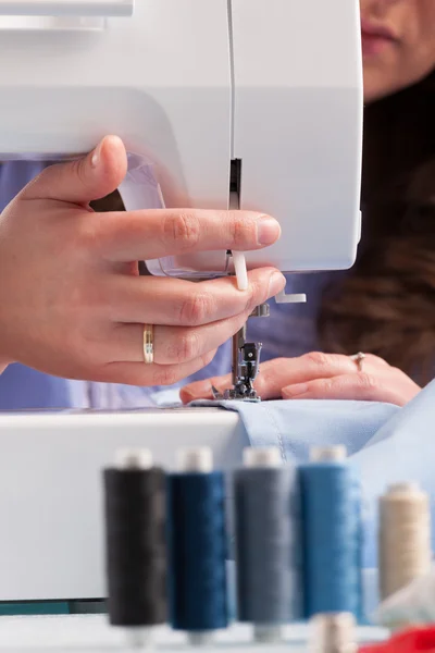 Hands on sewing machine with reels of colour threads and sewing — Stock Photo, Image