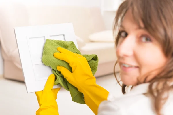 Beautiful young woman cleaning frame — Stock Photo, Image