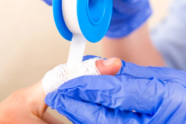 Hands in gloves putting on a bandage — Stock Photo, Image