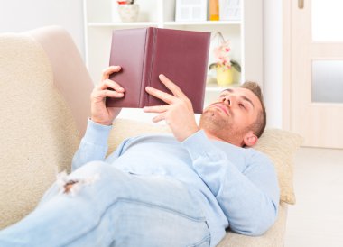 Genç adam kitap okuyor.