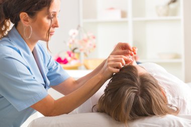 Acupuncture therapist applying acupuncture needle clipart