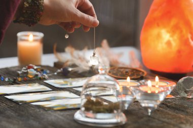 Falcı tarot kartlarının üzerinde sarkacı tutuyor.