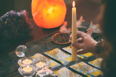 Tarot kartları elindeki aleti ve kristalleri psişik danışman ya da kehanet yöntemi olarak kullanıyor.