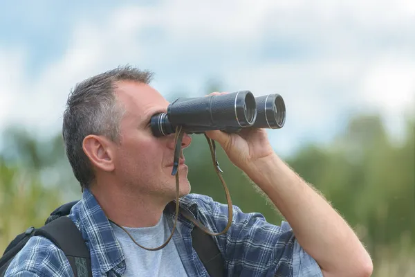 近视一个男人透过双筒望远镜看外面 — 图库照片