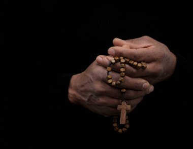 Siyahi adam Tanrı 'ya gri siyah arka planda el ele dua ederken insanların resimlerini stokluyor.