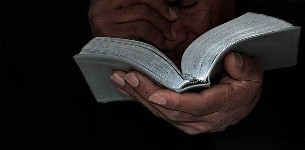 Praying to God with hand on bible with background with people stock photo