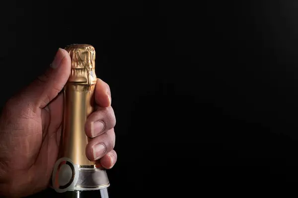 Hand Houden Een Gouden Fles Champagne Een Zwarte Achtergrond Voorraad — Stockfoto