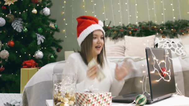 Noel Baba şapkalı kadın dizüstü bilgisayarlı 5 dolarlık banknotla evde eğleniyor, online alışveriş yapıyor veya yılbaşında kumar oynuyor. — Stok video