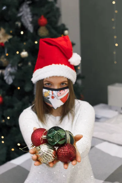 Decoração de Natal em mãos de mulher em chapéu de santa e máscara protetora de tecido festivo, novo normal no Ano Novo ou xmas — Fotografia de Stock