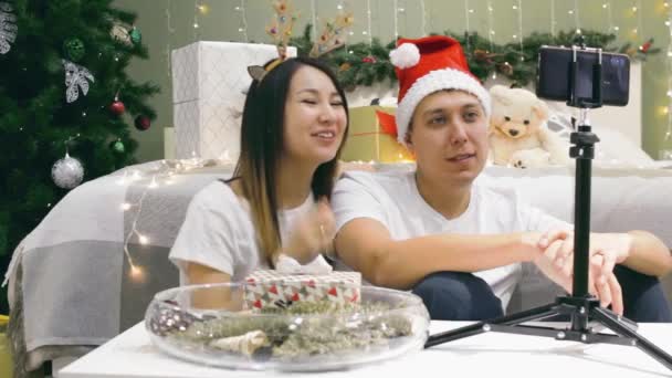 Unge forskelligartede par taler på telefon via videoopkald hjemme, moderne teknologi til festlig online konference til jul – Stock-video