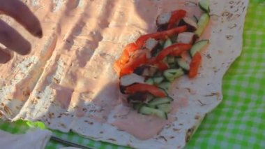 Kadın eli, kış pikniğinde sebze ve et rulosu, salatalık dilimleri ve rulo soslu pide biftek toplar.
