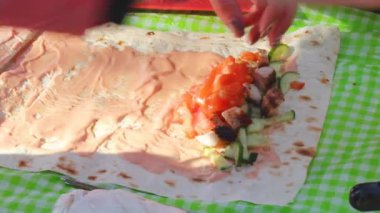 Kadın elleri kış pikniğinde sebze ve et rulosu, salatalık dilimleri ve soslu peynirli biftek pişirir.