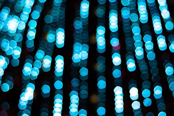 Şehir merkezindeki Central Park 'ta Noel ağacının üzerindeki şenlikli mavi xmas ışıkları, kış akşamları, parlak çelenk süslemeleri, şehir merkezindeki parlak bokeh' te parlıyor, odak dışında.