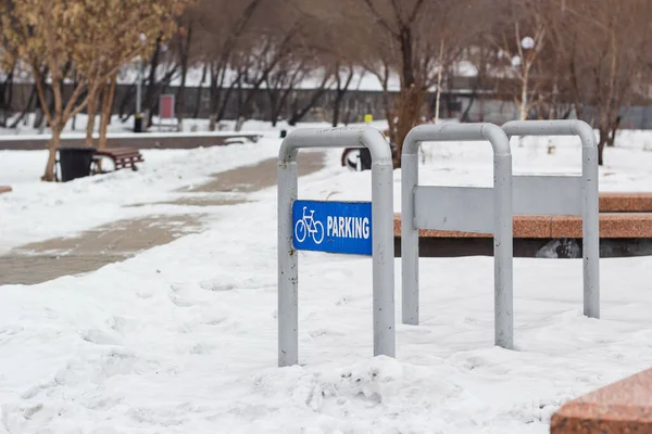 Estacionamiento de bicicletas vacío en el parque público nevado en invierno frío, estación de bicicletas urbanas en la zona de recreación de la ciudad, tiempo nublado — Foto de Stock