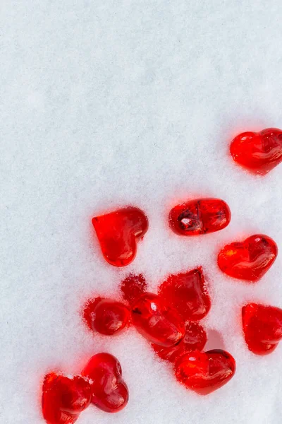 Размещение ярко-красных стеклянных сердец на порошкообразном снегу в зимний день, символ любви, праздничная концепция Дня Святого Валентина — стоковое фото