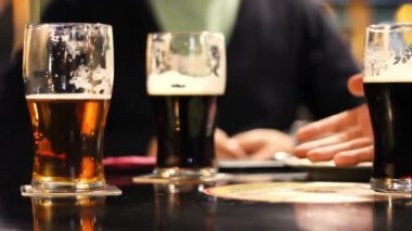 Arka planda bira bardakları, barda içki içmek, bira bardakları, masada hafif bira, karanlık sahne.