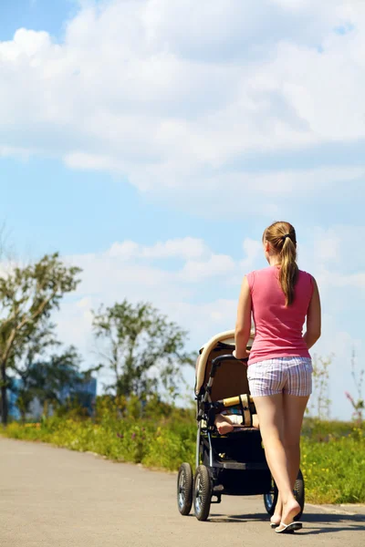 Jonge moeder met kinderwagen — Stockfoto