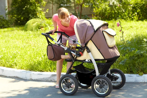 Jonge moeder met kinderwagen — Stockfoto