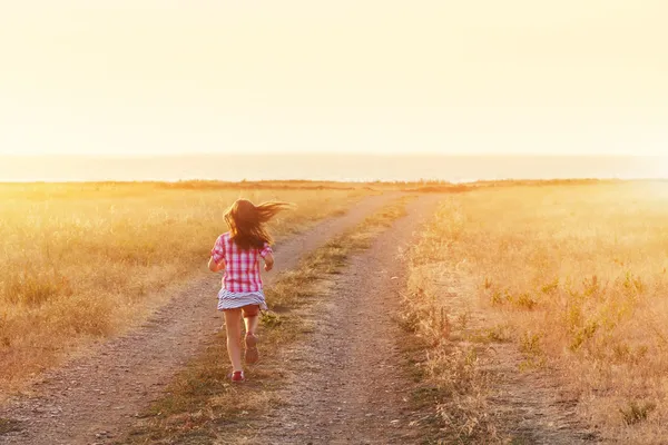 Kleines Mädchen läuft in beleuchtete Wiese — Stockfoto