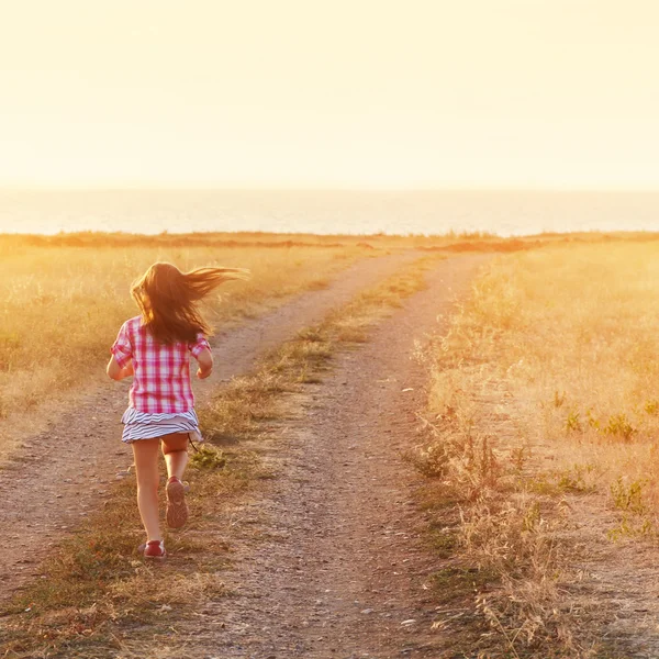 Niña corriendo en prado retroiluminado —  Fotos de Stock