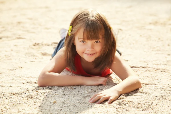 Meisje liggend op het zand — Stockfoto